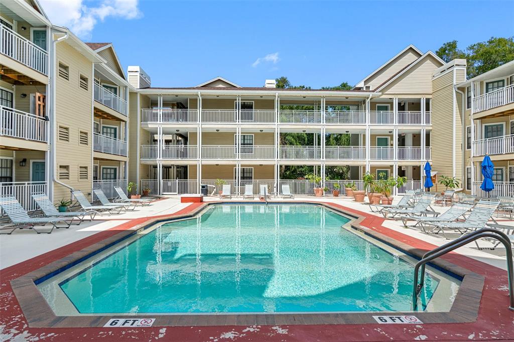An outdoor swimming pool is surrounded by a multi-story apartment building with white balconies — 1000 W HORATIO STREET UNIT 114, TAMPA, FL