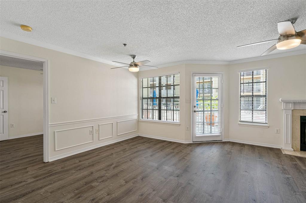 A living room with wood-look flooring, wainscoting, two ceiling fans, and a glass patio door — 1000 W HORATIO STREET UNIT 114, TAMPA, FL