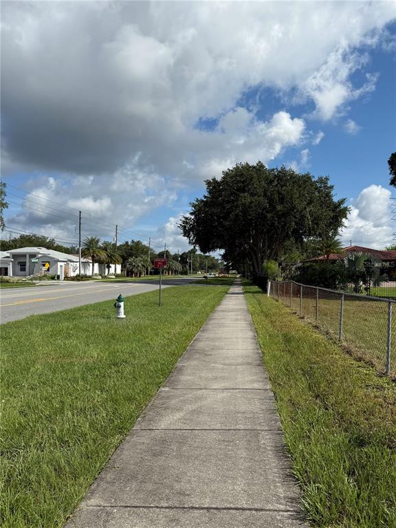 A concrete sidewalk runs alongside a grassy verge, a road, and a chain-link fence — ECONLOCKHATCHEE TRAIL S, ORLANDO, FL