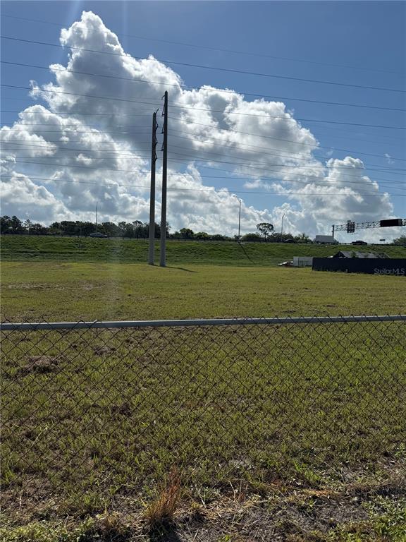 A grassy vacant lot is enclosed by a chain-link fence beneath high-voltage power lines — ECONLOCKHATCHEE TRAIL S, ORLANDO, FL