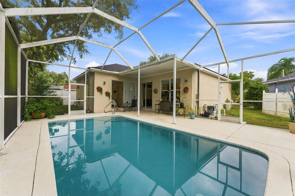 A backyard swimming pool enclosed by a screened lanai attached to a single-story house — 491 BRILAND STREET, TARPON SPRINGS, FL