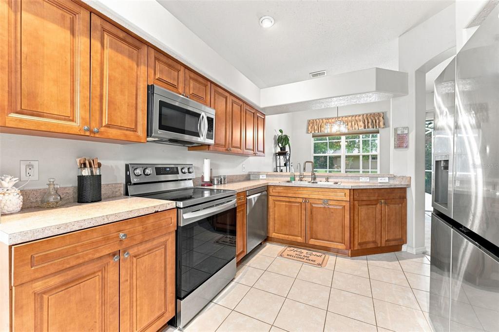 A single-story house with a two-car garage, concrete driveway, and mature trees in the yard — 491 BRILAND STREET, TARPON SPRINGS, FL