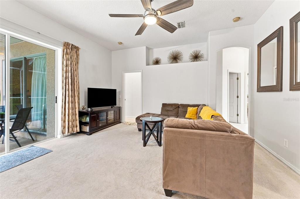 A hallway with a shoe rack and runner rug leads to a living room with patio access — 491 BRILAND STREET, TARPON SPRINGS, FL