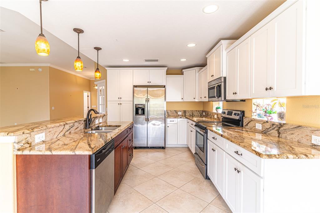 A kitchen features white cabinets, granite countertops, stainless steel appliances, and a central island — 3715 SEBRING PARKWAY, SEBRING, FL