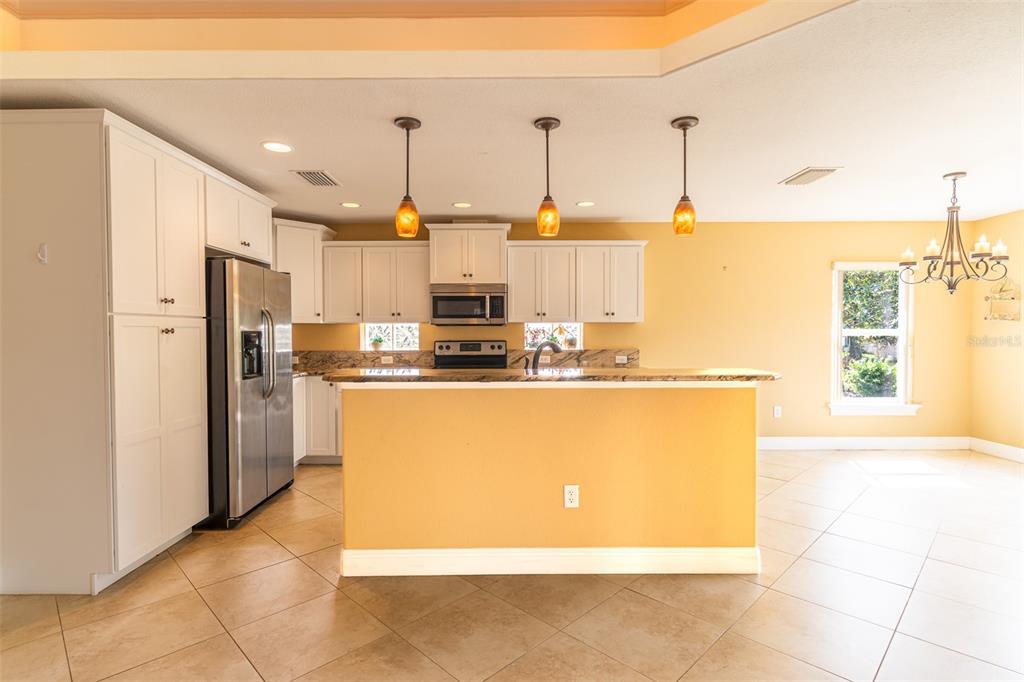 A kitchen with white cabinets, granite countertops, stainless steel appliances, and yellow walls — 3715 SEBRING PARKWAY, SEBRING, FL