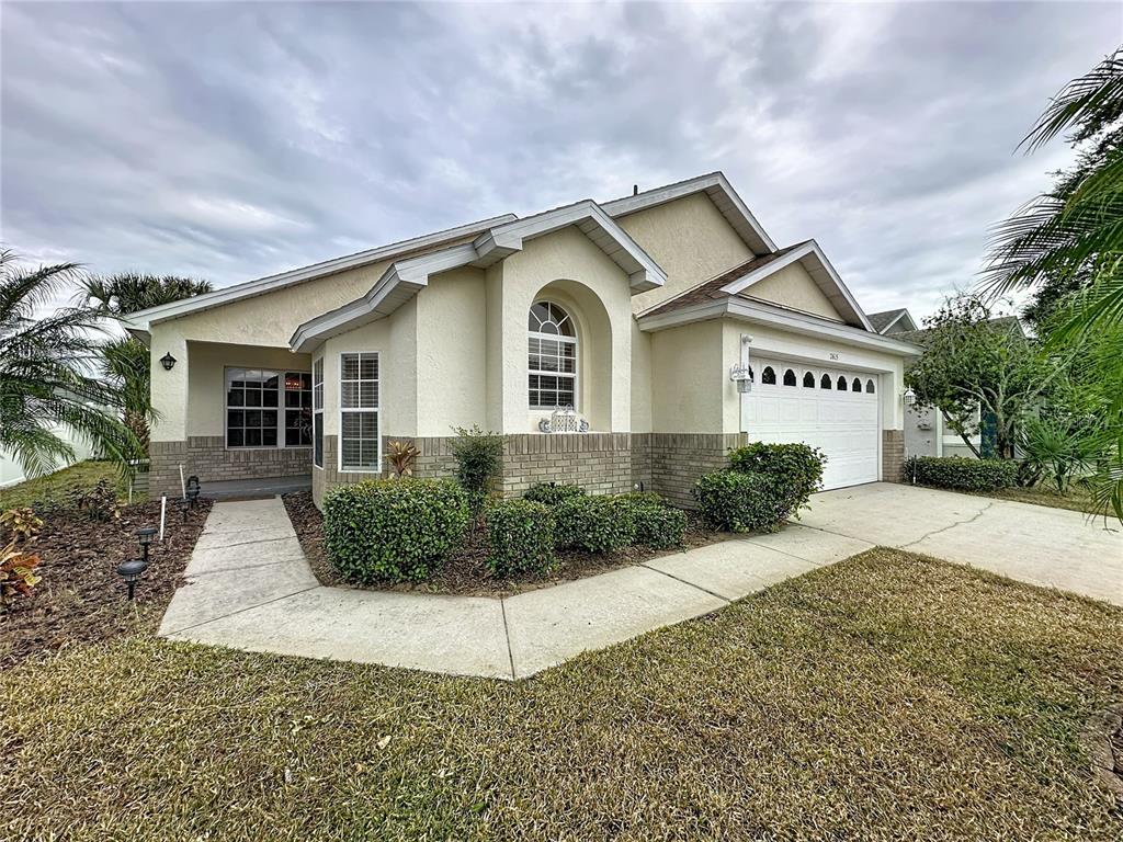 A single-story house with a beige stucco exterior, brick accents, and a two-car garage — 2615 SUMMER CREEK DRIVE, KISSIMMEE, FL