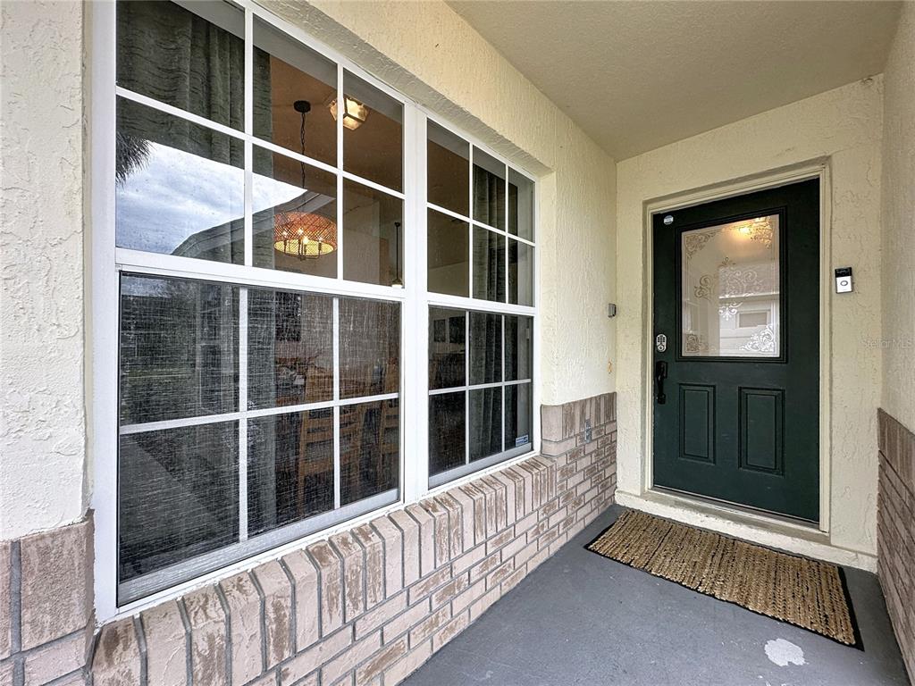 A front porch features a dark green door with a window and a large window — 2615 SUMMER CREEK DRIVE, KISSIMMEE, FL