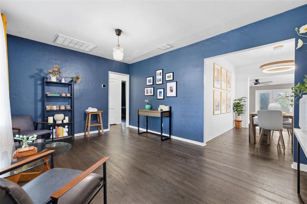 A living room with dark blue walls, dark wood flooring, and a dining area beyond — 1209 E CRENSHAW STREET, TAMPA, FL
