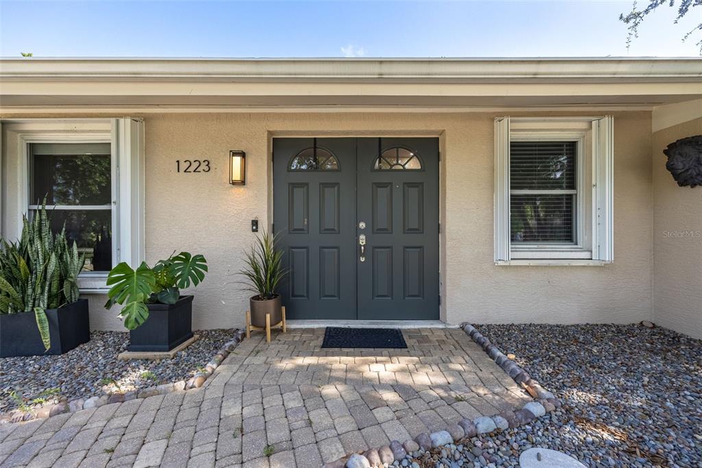 The exterior of a house features a double front door, windows, and a stone walkway — 1223 BILTMORE DRIVE, FORT MYERS, FL