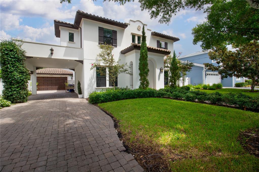A two-story white stucco house with a paved driveway, attached garage, and landscaped front yard — 3917 W SAN LUIS STREET, TAMPA, FL