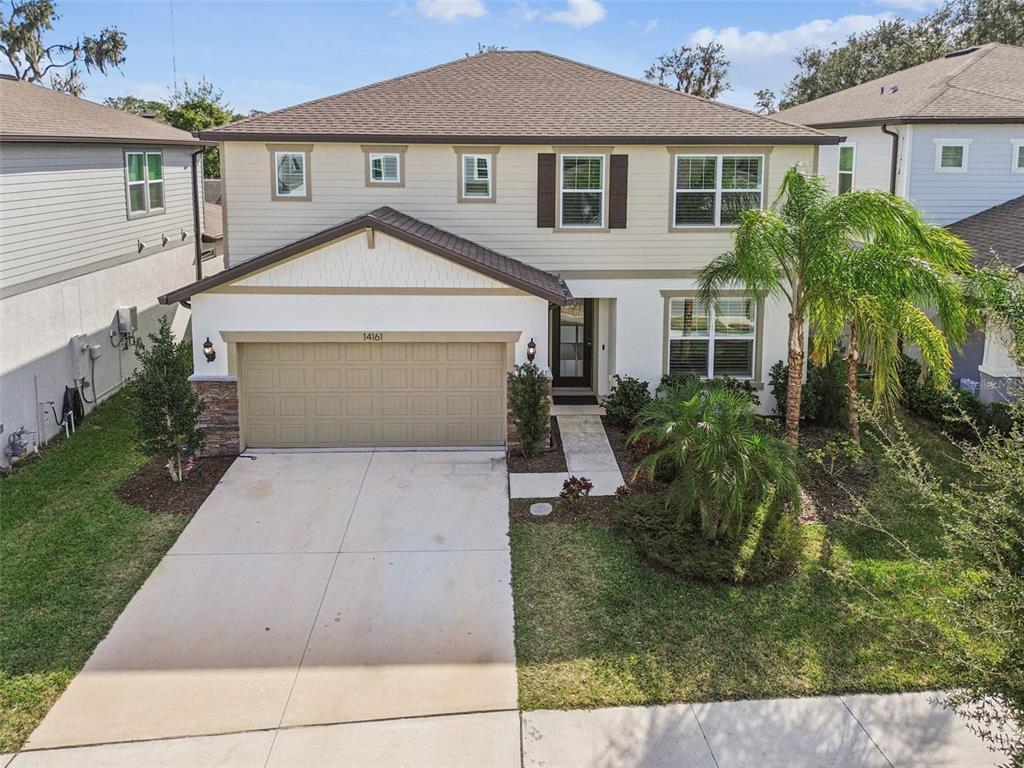 An exterior view of a two-story suburban house with a tan garage and beige siding — 14161 HAMMOCK CREST WAY, RIVERVIEW, FL