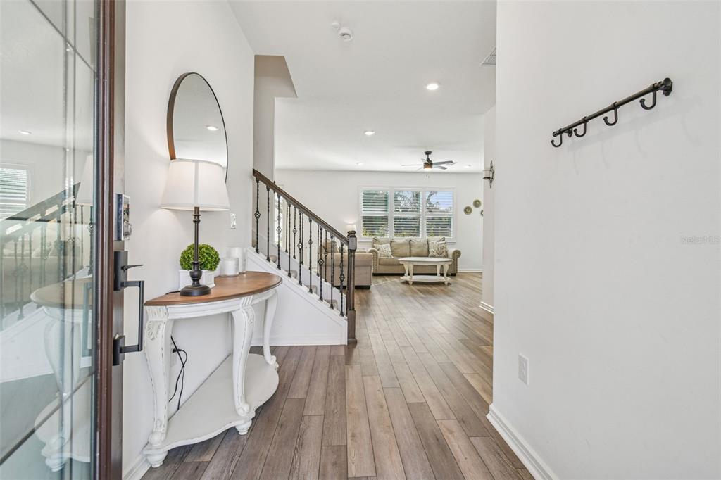 An entryway features a wood-topped console table, a staircase with iron railings, and hardwood flooring — 14161 HAMMOCK CREST WAY, RIVERVIEW, FL