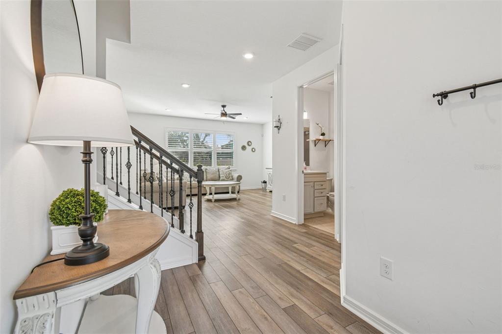 A view from a hallway looking into a living room with wood-look flooring and stairs — 14161 HAMMOCK CREST WAY, RIVERVIEW, FL