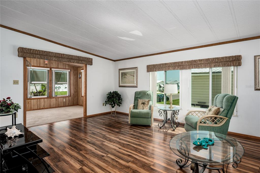 A living room with wood-look flooring, two green armchairs, and a view into another room — 4215 14TH STREET E, ELLENTON, FL