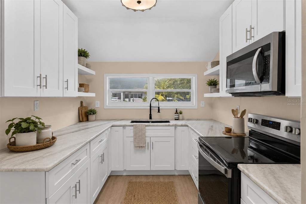A room with light beige walls, wood-look flooring, a ceiling fan, and an open kitchen — 116 S GLENWOOD AVENUE, ORLANDO, FL