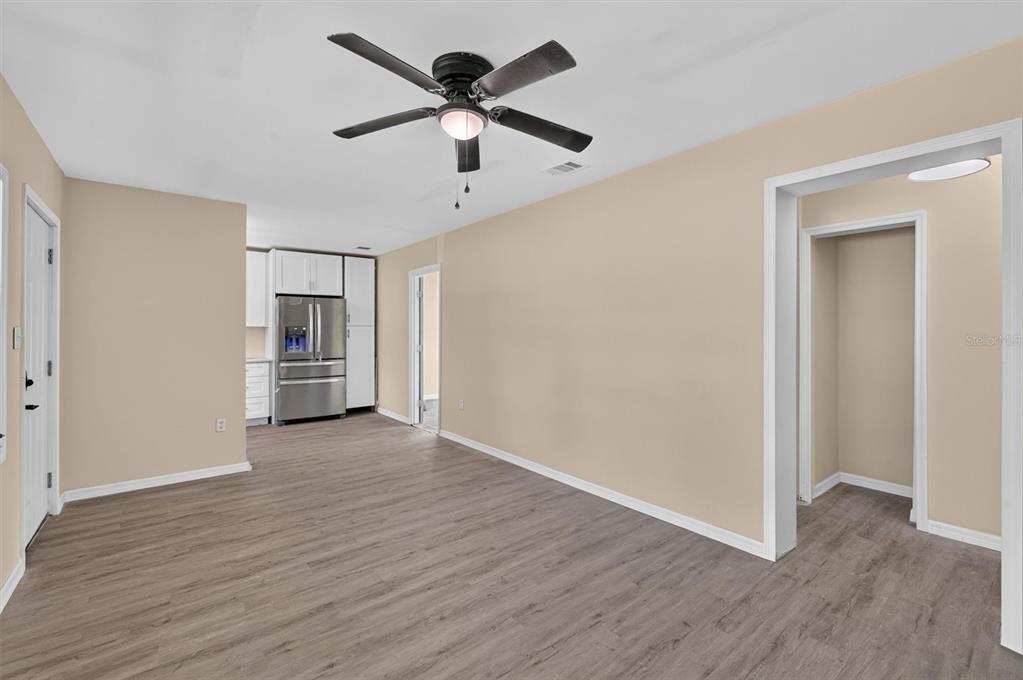 A living room with light wood-look flooring, a ceiling fan, and an adjacent white kitchen — 116 S GLENWOOD AVENUE, ORLANDO, FL