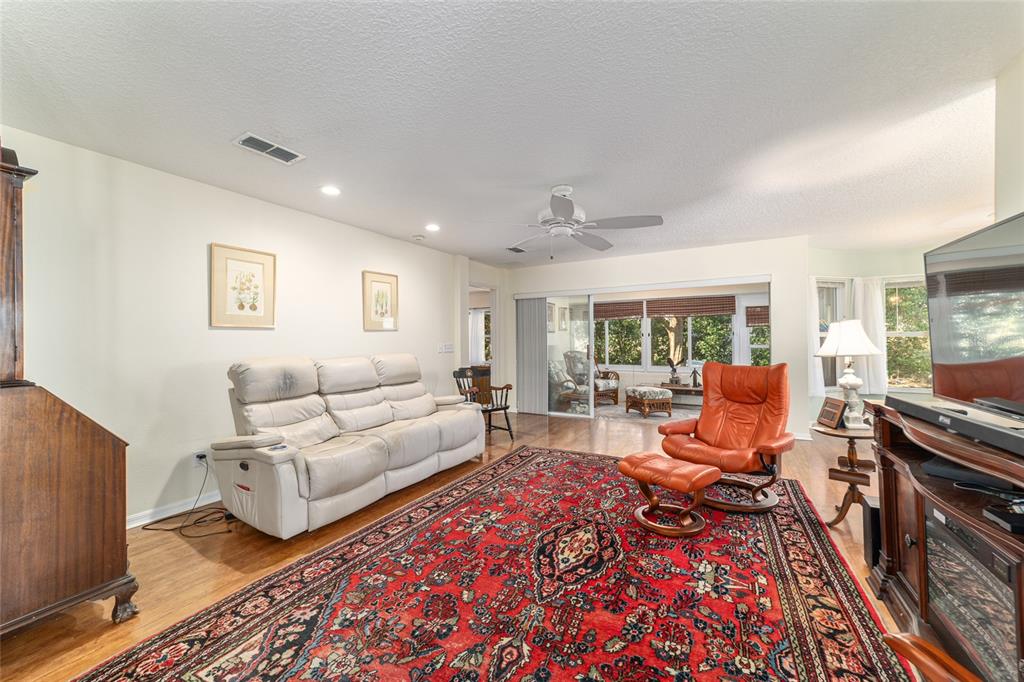 A living room features a large red patterned rug, a white sofa, and an orange chair — 9686 SW 92ND PLACE ROAD, OCALA, FL