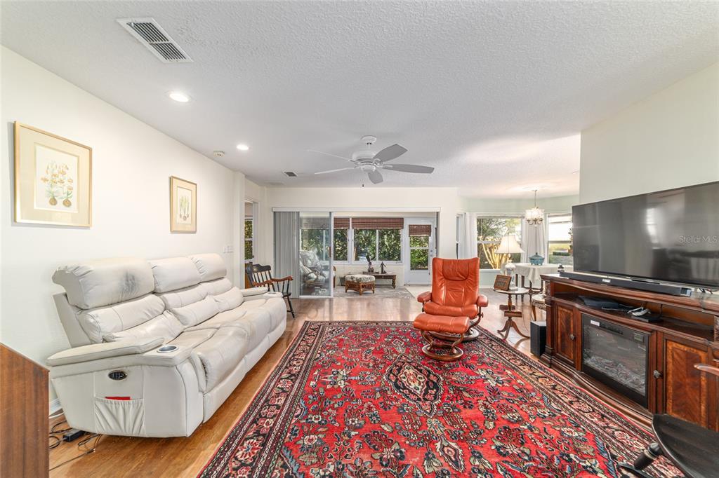 A living room features a white reclining sofa, a red patterned rug, and a television — 9686 SW 92ND PLACE ROAD, OCALA, FL