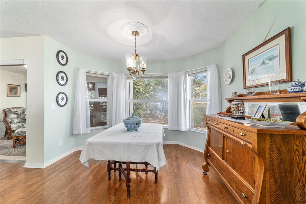 A dining room features a white-clothed table, a wooden sideboard, and a bay window — 9686 SW 92ND PLACE ROAD, OCALA, FL