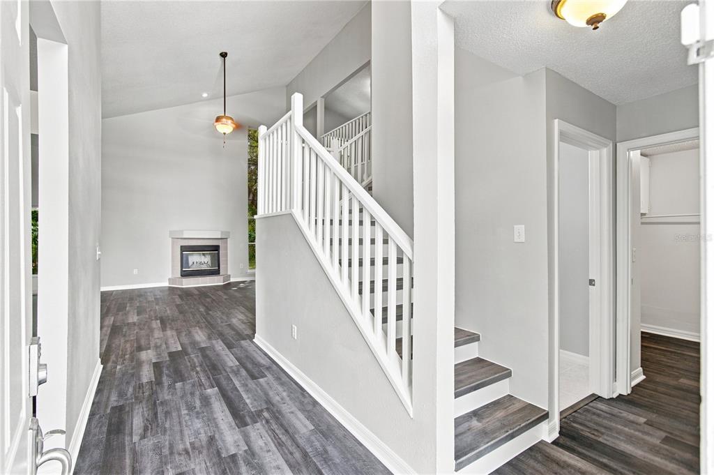 An entryway features gray wood-look flooring, a white staircase with a railing, and a fireplace — 13417 BEECHBERRY DRIVE, RIVERVIEW, FL