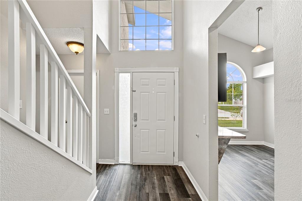 An entryway features a white front door, a staircase with white railings, and wood-look flooring — 13417 BEECHBERRY DRIVE, RIVERVIEW, FL