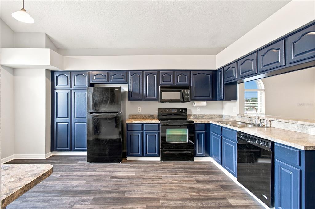 A kitchen features dark blue cabinets, black appliances, and wood-look flooring with laminate countertops — 13417 BEECHBERRY DRIVE, RIVERVIEW, FL