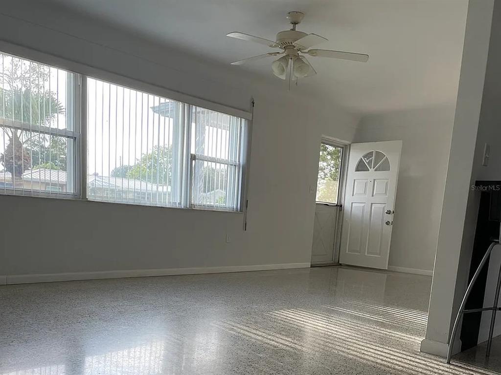 A living room with light-colored walls, a ceiling fan, large windows, and terrazzo flooring — 5003 58TH WAY N, KENNETH CITY, FL