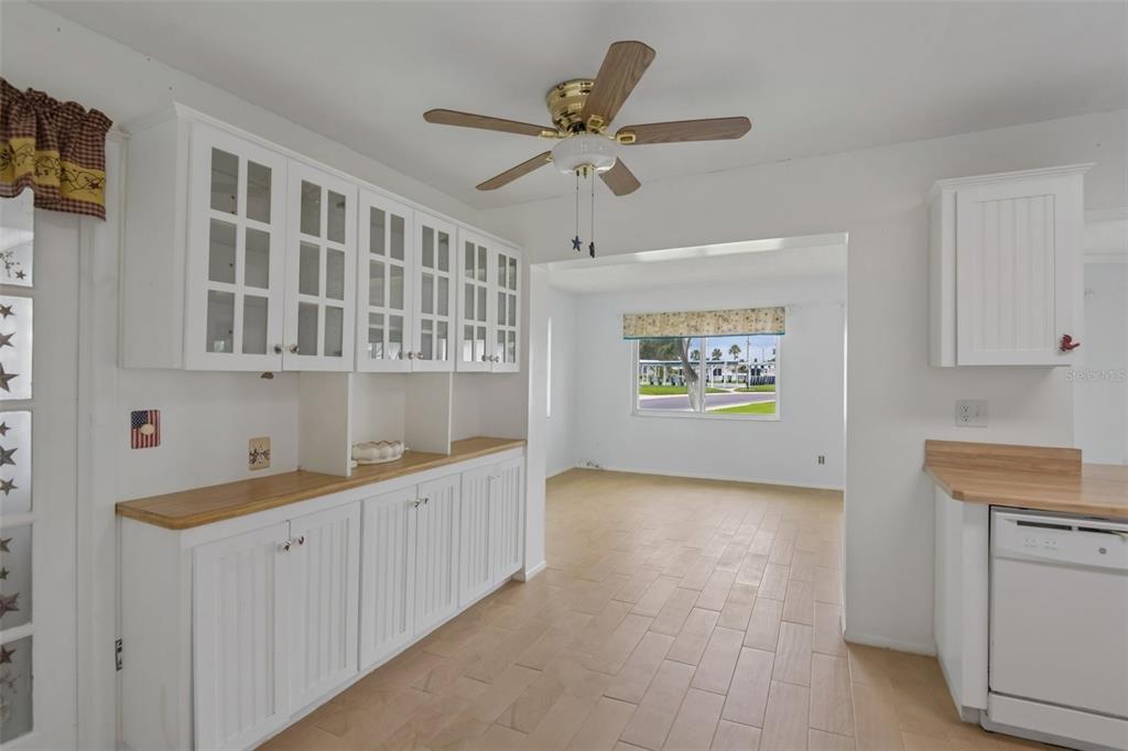 A kitchen with white cabinets, wood countertops, and a ceiling fan opens to a room — 3549 98TH AVENUE N, PINELLAS PARK, FL