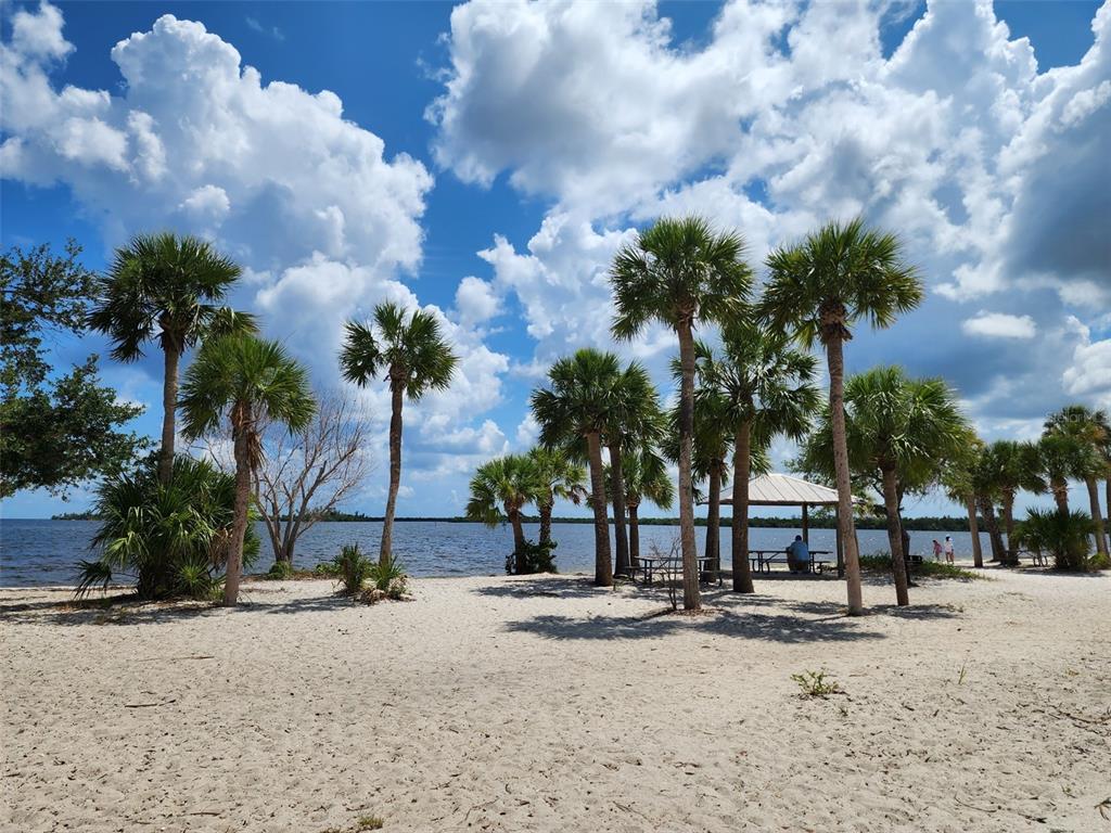 A sandy beach area features numerous palm trees and a picnic pavilion overlooking the water — 3135 CABARET STREET, PORT CHARLOTTE, FL