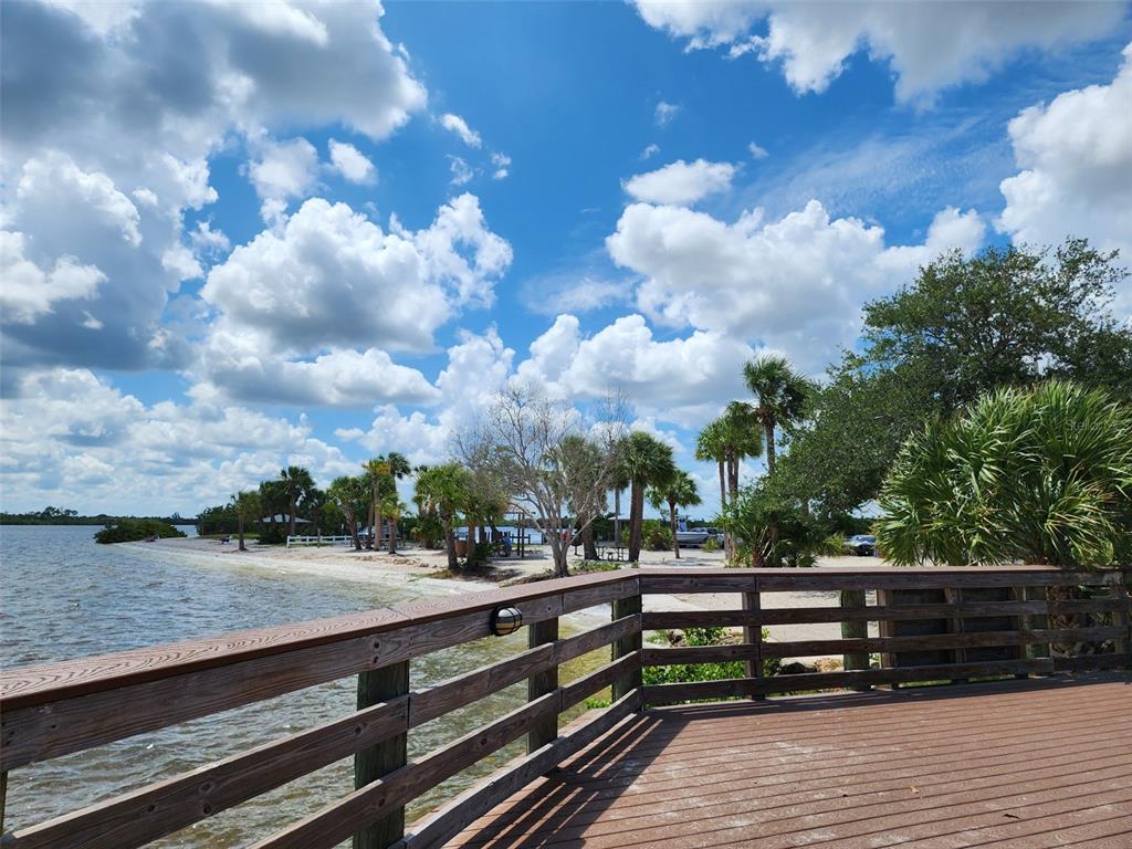 A wooden deck overlooks a sandy beach, palm trees, and a body of water — 3135 CABARET STREET, PORT CHARLOTTE, FL