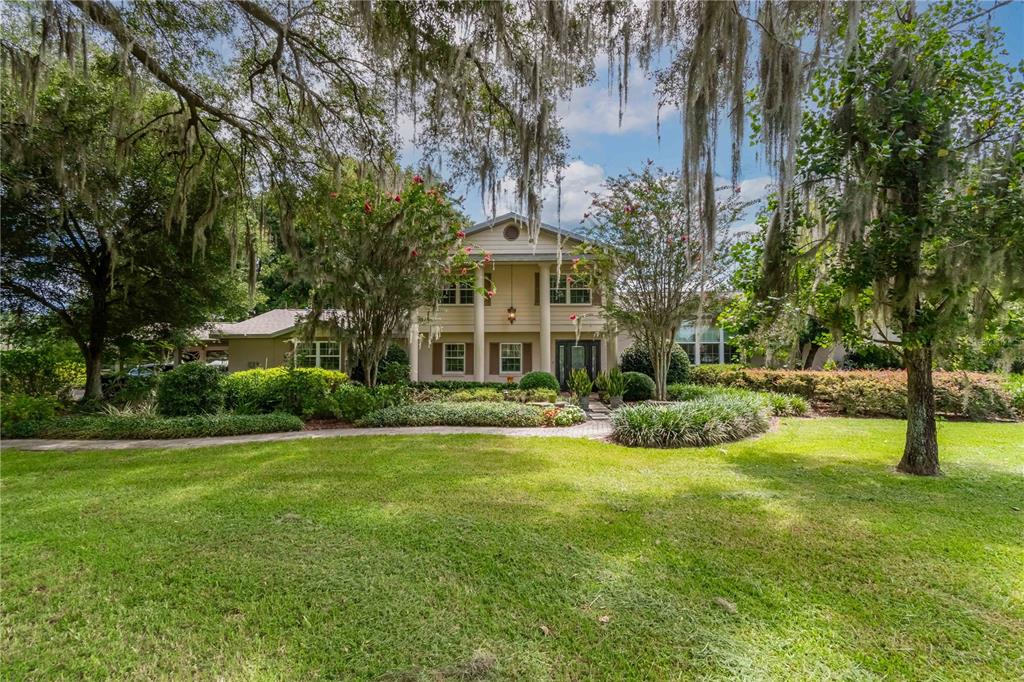 A two-story house with a columned porch is surrounded by trees and a green lawn — 12500 NW 100TH STREET, OCALA, FL