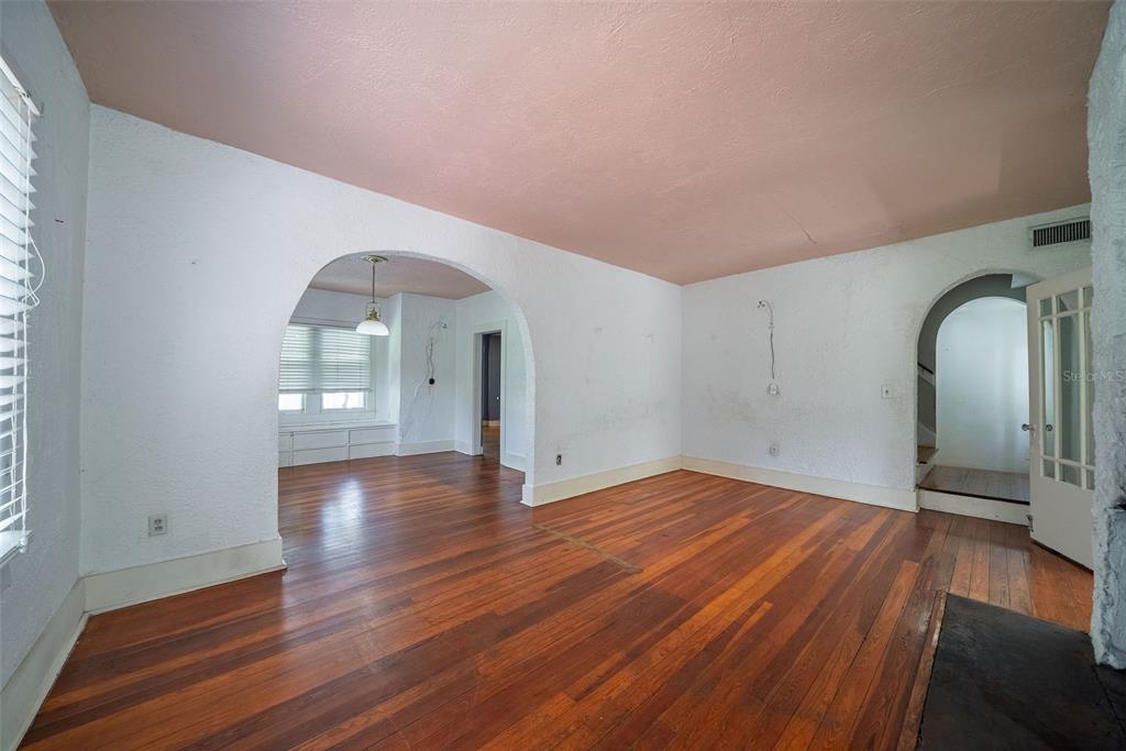 An empty living room features hardwood floors, white walls, a pink ceiling, and two arched doorways — 813 GREENWOOD STREET, ORLANDO, FL