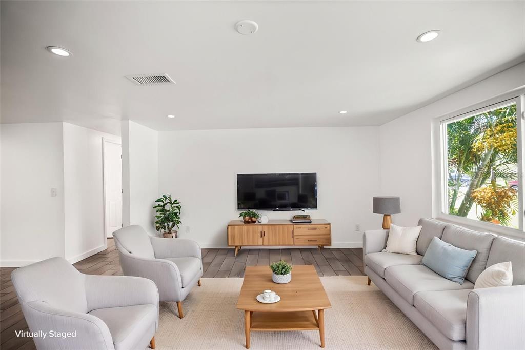 A living room features light gray furniture, a wooden coffee table, and a wall-mounted television — 5646 QUIST DRIVE, PORT RICHEY, FL