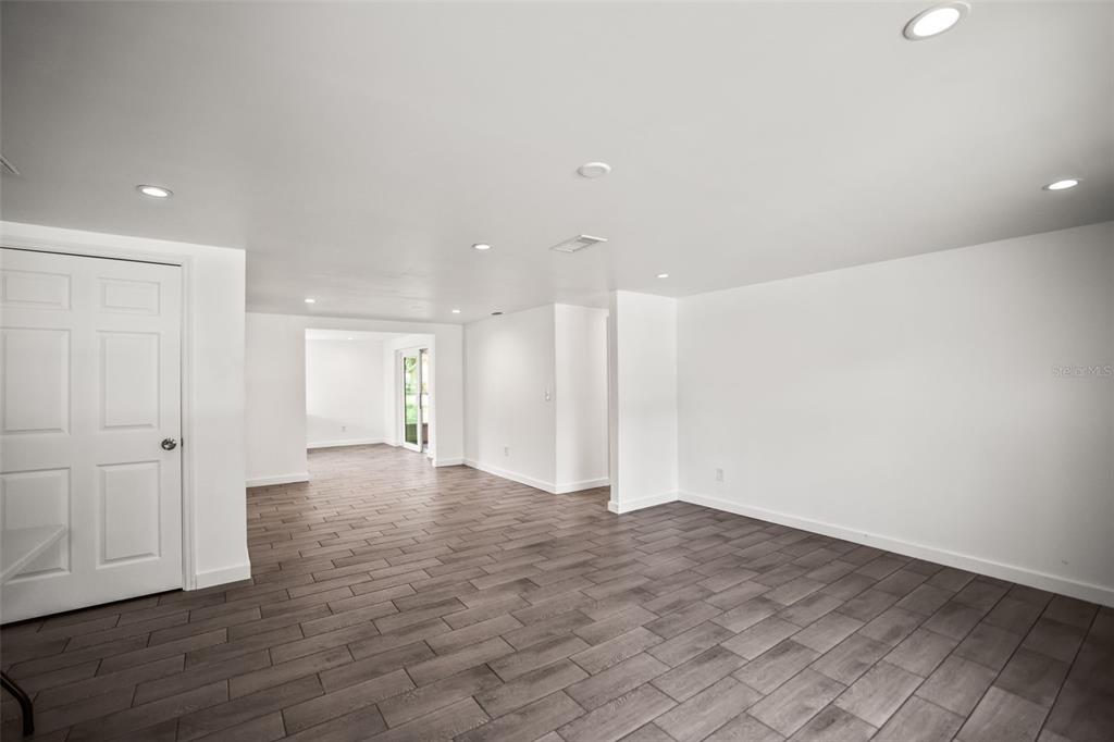 An interior room with white walls, recessed lighting, and gray wood-look tile flooring — 5646 QUIST DRIVE, PORT RICHEY, FL
