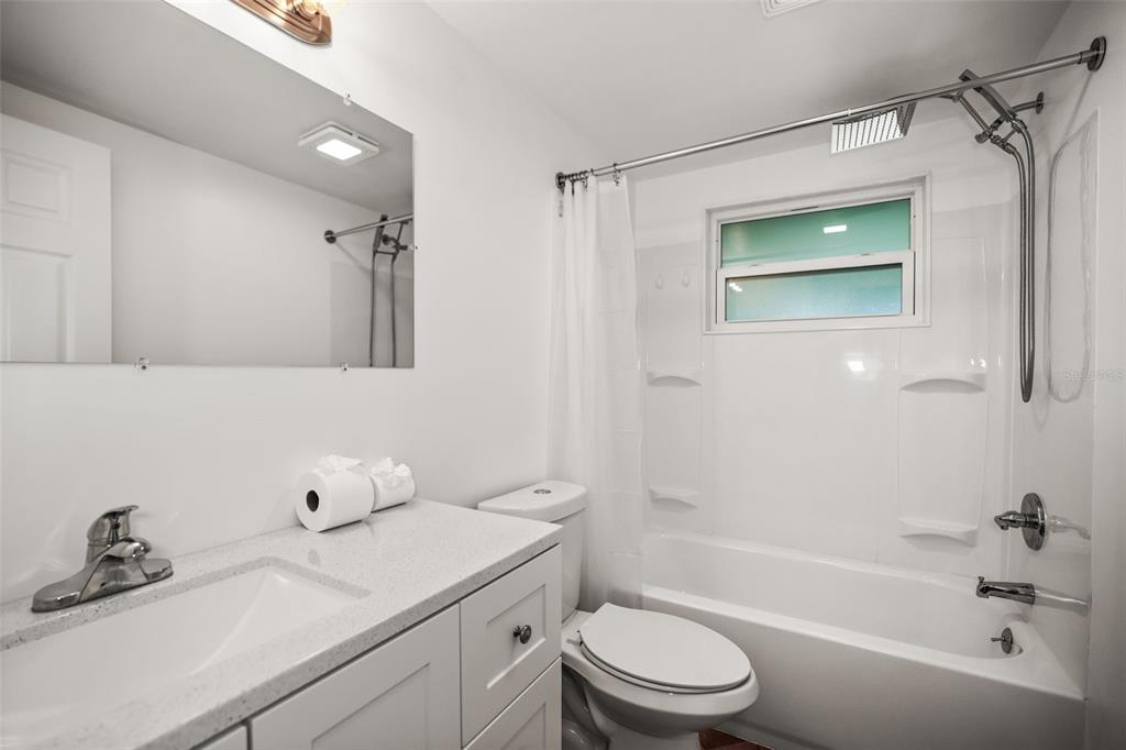 A bathroom features a white vanity, a toilet, and a tub-shower combination with a window — 5646 QUIST DRIVE, PORT RICHEY, FL