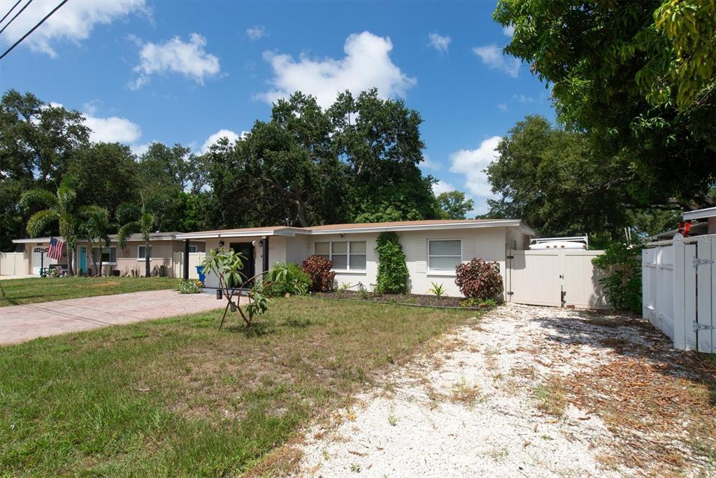 A single-story house with a white exterior, a gravel driveway, and a fenced side yard — 12812 LAKE DRIVE, LARGO, FL