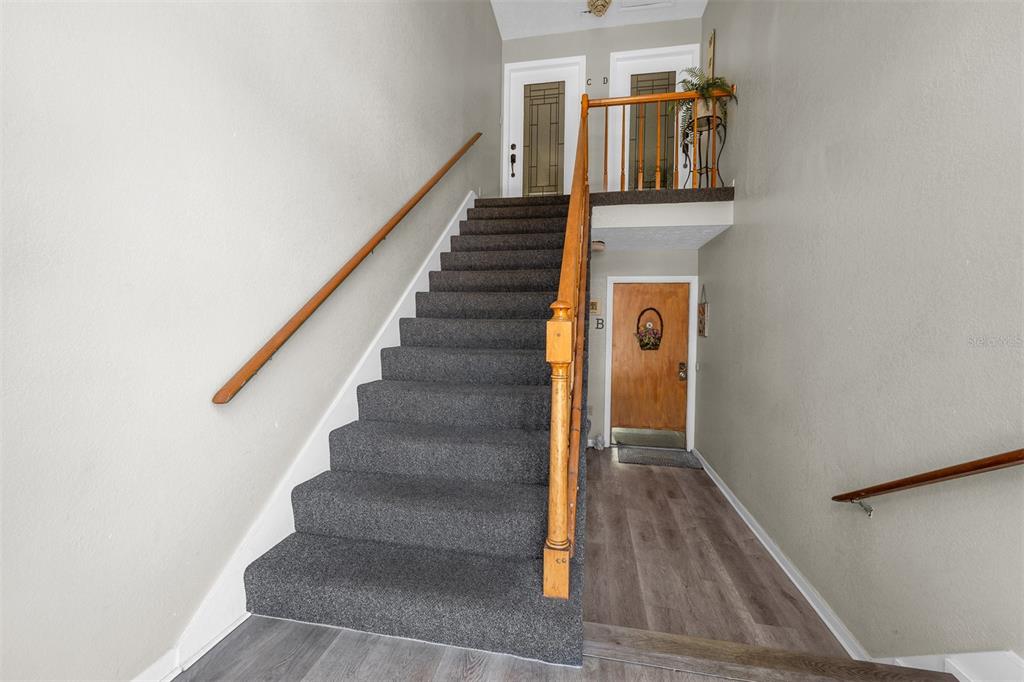 A carpeted staircase leads to an upper landing with a wooden door and light flooring — 4214 LAKE UNDERHILL ROAD UNIT C, ORLANDO, FL