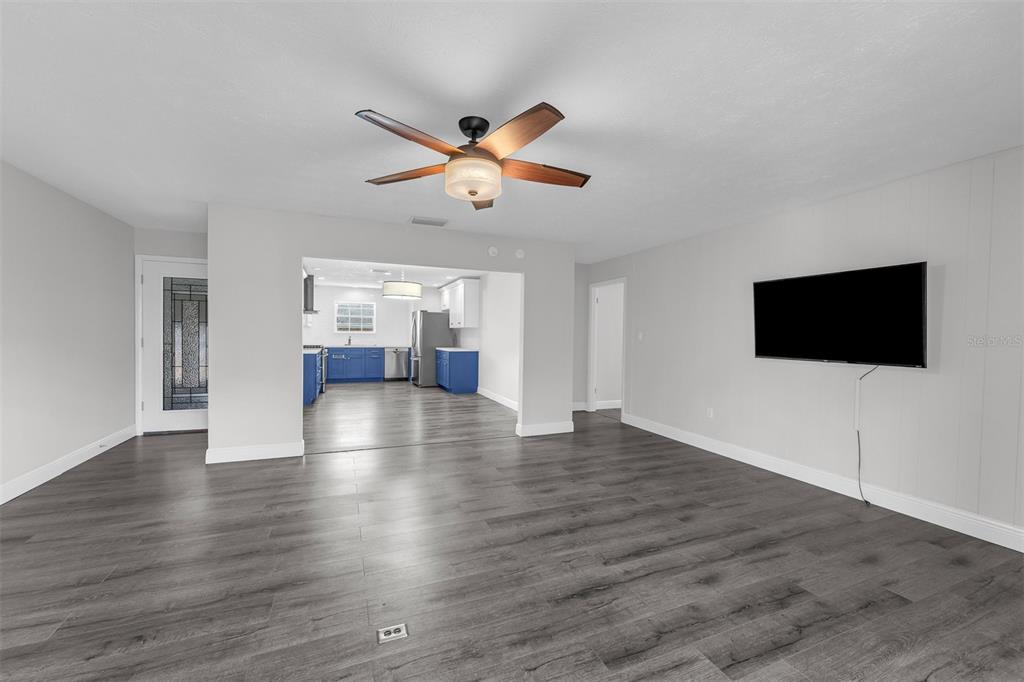 A living room with gray wood-look flooring, a ceiling fan, and a wall-mounted television — 4214 LAKE UNDERHILL ROAD UNIT C, ORLANDO, FL