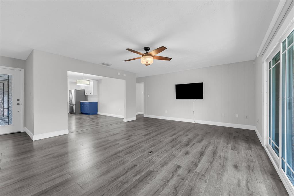 A living room with gray wood-look flooring, a ceiling fan, and a wall-mounted television — 4214 LAKE UNDERHILL ROAD UNIT C, ORLANDO, FL