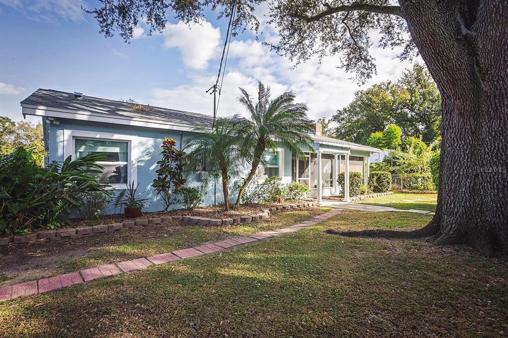 A light blue single-story house features a brick walkway, palm trees, and a large tree — 2614 FAIRVIEW AVENUE, SEFFNER, FL