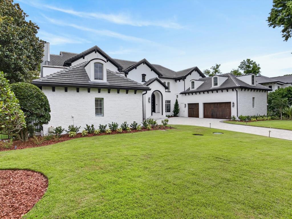 A white brick house with a dark shingled roof and a three-car garage — 9832 LAUREL VALLEY DRIVE, WINDERMERE, FL