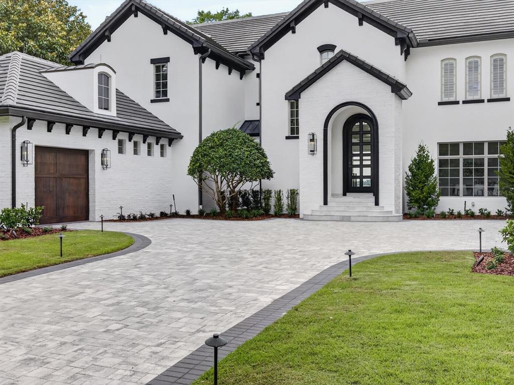 A white brick house with a dark roof, arched front door, and paved driveway — 9832 LAUREL VALLEY DRIVE, WINDERMERE, FL
