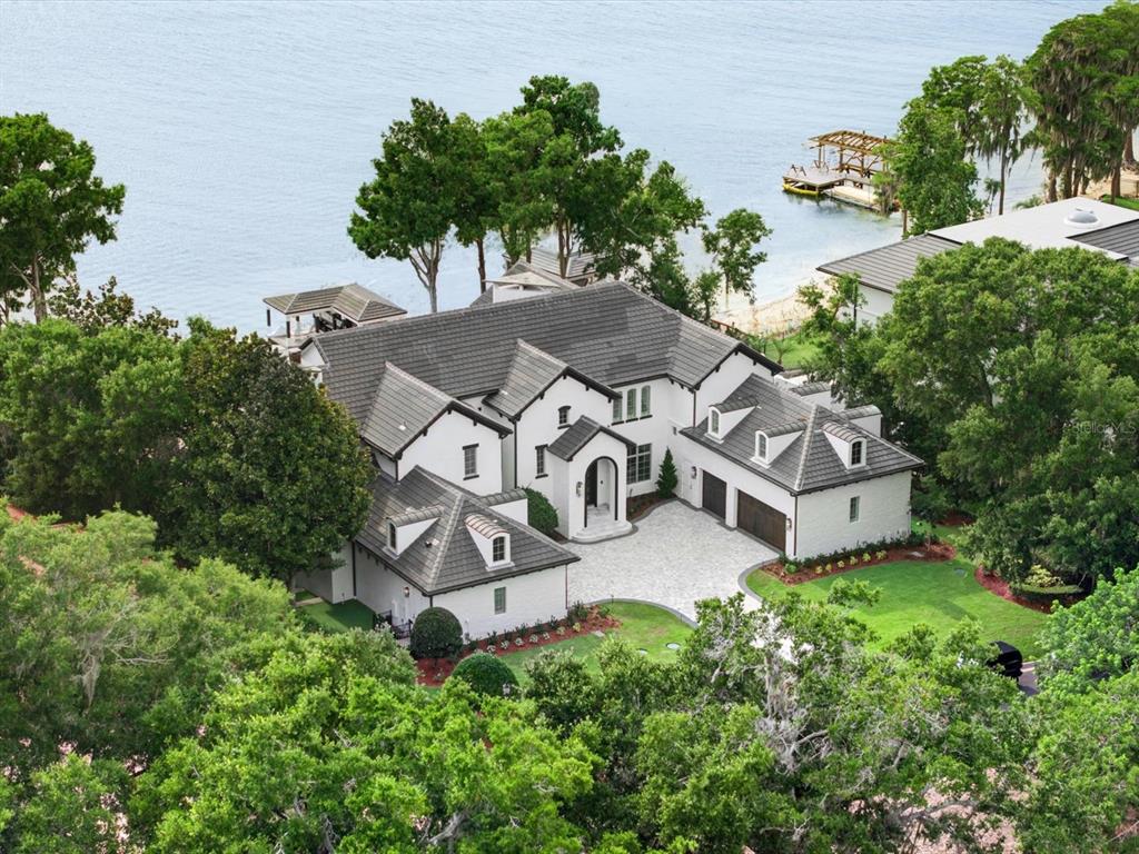 An aerial view shows a large white house with a dark roof near a lake — 9832 LAUREL VALLEY DRIVE, WINDERMERE, FL