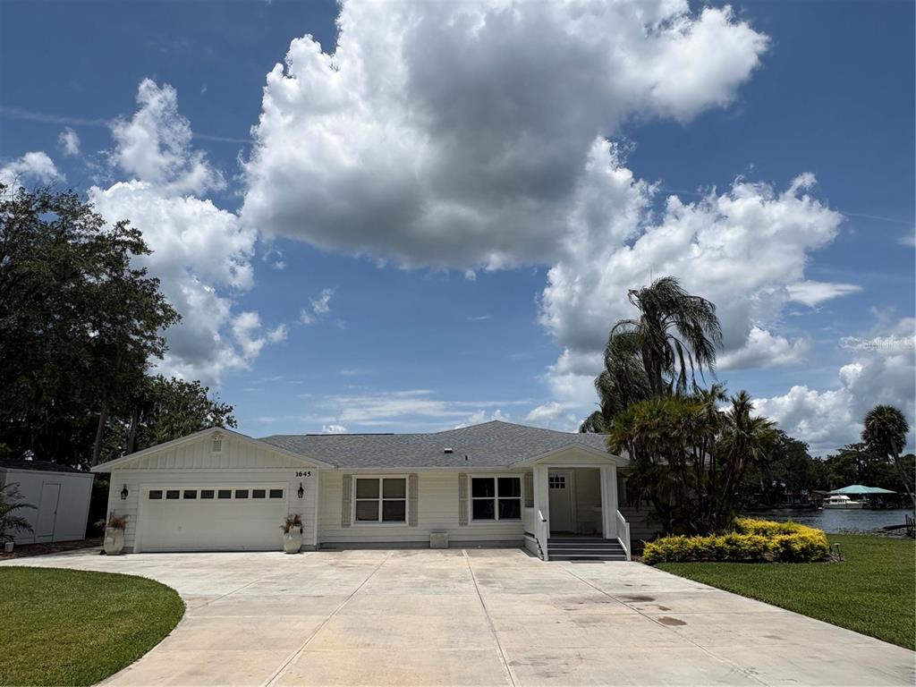 A sunset view over a lake with palm trees and a grassy lawn in foreground — 1645 SPRING GARDEN DRIVE, ASTOR, FL