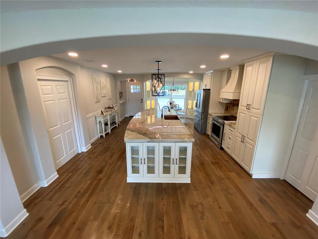 A single-story white house with a large concrete driveway, attached garage, and waterfront backyard — 1645 SPRING GARDEN DRIVE, ASTOR, FL
