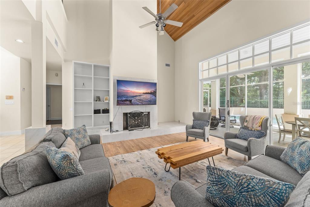 A living room features a high vaulted ceiling, a fireplace with a television, and large windows — 5073 LATROBE DR, WINDERMERE, FL