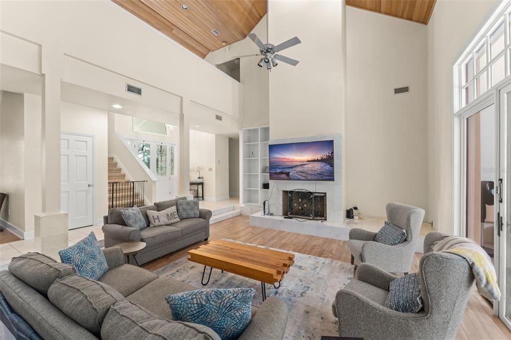A living room features a vaulted wood ceiling, a fireplace with a television, and furniture — 5073 LATROBE DR, WINDERMERE, FL