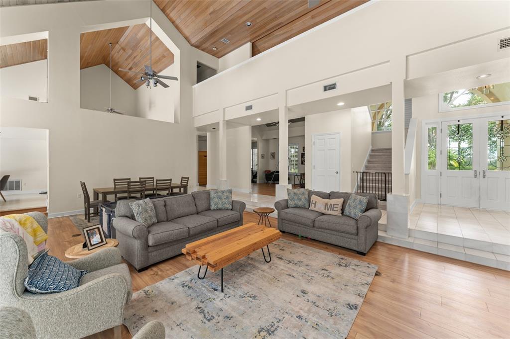 A spacious living room features vaulted wood ceilings, a dining area, and a staircase — 5073 LATROBE DR, WINDERMERE, FL
