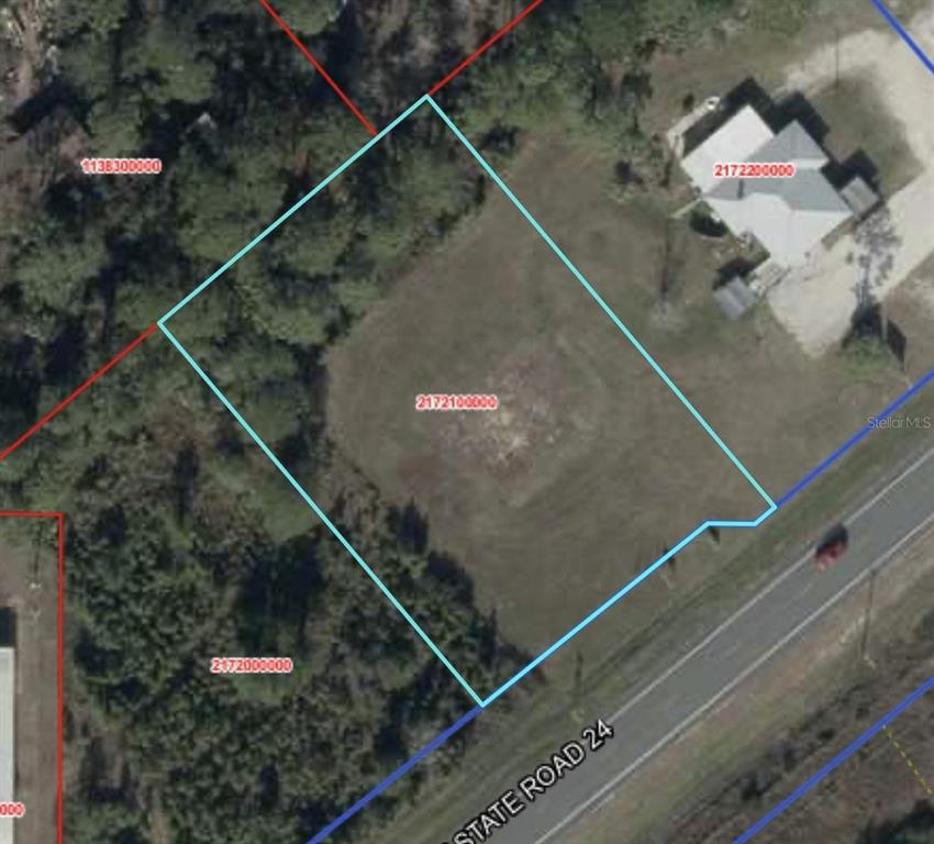 This is an aerial map showing a vacant lot outlined in blue along State Road 24 — SR 24, CEDAR KEY, FL