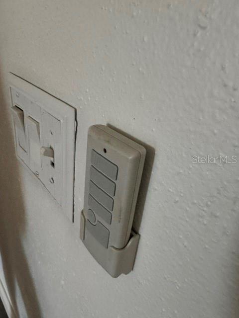 A wall-mounted ceiling fan remote control sits next to a double light switch — 2602 GRAMERCY DRIVE, DELTONA, FL